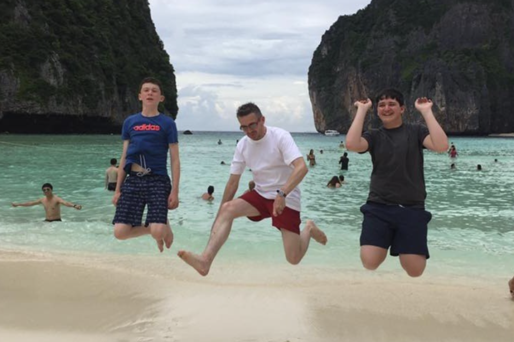 Father and sons jumping on a beach in Thailand. HomeExchange for teachers.