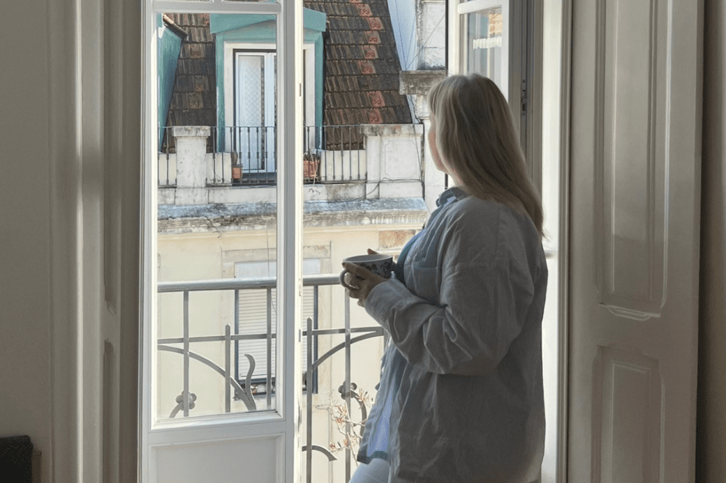 Young woman with mug overlooking houses. HomeExchange influencer. 