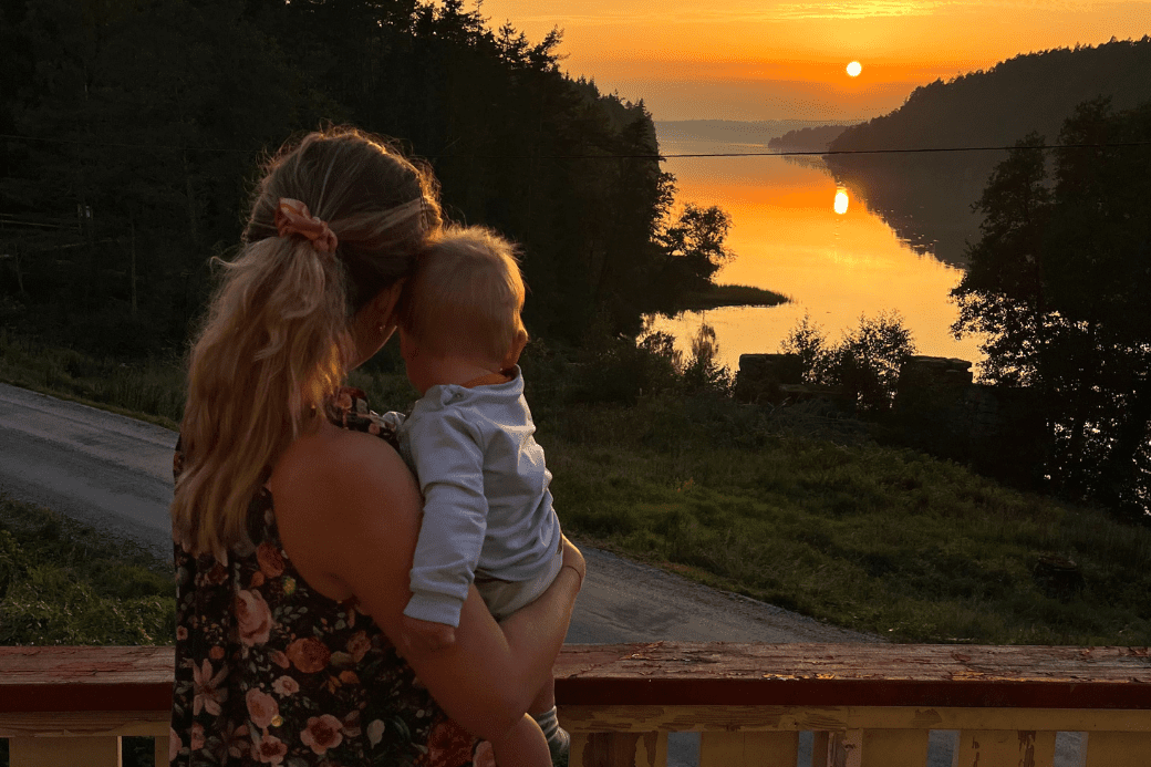 HomeExchange influencer Tereza. Woman with baby watching sunset over lake.